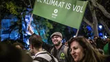 Demonstratie waarbij een demonstrant een doek omhoog houdt met de tekst: De klimaat is vol