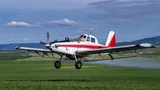 Een propellervliegtuig spuit gif over landbouwgewassen.