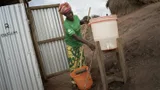 Therese, een gezondheidswerker van Oxfam, maakt latrines schoon.