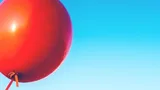 Foto van een rode ballon in de lucht.
