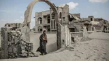 Foto van een vrouw, die tussen ruïnes loopt in Jemen