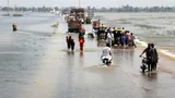 Foto van mensen die een overstroomde snelweg oversteken in het Dadu-district, provincie Sindh, Pakistan.