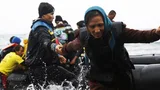 Vluchtelingen stappen uit een rubberboot en komen aan op Lesbos.