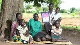 Op de foto (vlnr): Buurvrouw Margret, die helpt met de tweeling Apio Stella Rose en Acen Florance Jannet (beiden op schoot), vader Ogwang James met het portret van zijn overleden vrouw Akol Stella Rose, hun dochter Asio Everlyn en zoon Ogwang Brain.