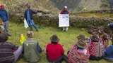 Farmers in Peru sit outside and listen to a presentation.