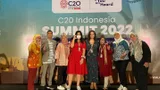 People from the Oxfam delegation stand in front of a banner of the C20 Bali summit.