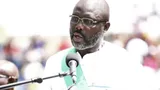 President George Weah speaks in front of a microphone.