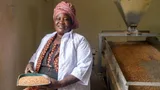 Florence Okot holding basket with grains