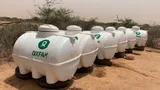 Watertanks met het Oxfam logo op een zandvlakte.