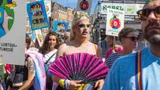 Een drag queen tussen mensen met protestborden tijdens Pride demonstratie