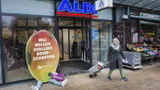 Een kartonnen protestbord in de vorm van een mango met daarop "wij willen eerlijke boodschappen" bij de ingang van de Aldi