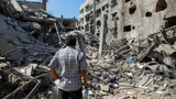 Foto van een man die naar het puin kijkt van een gebombardeerd gebouw in Gaza