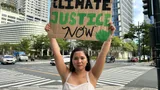 Klimaatactivist Marinel houdt een bord met 'Climate Justice Now' omhoog