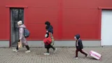 Migranten lopen met hun spullen langs een gebouw