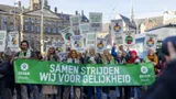 Demonstranten van het Oxfam Novib team met een groot spandoek met daarop 'Samen strijden wij voor gelijkheid'