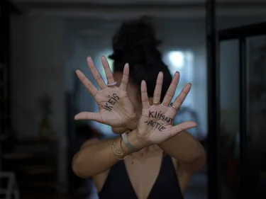 Afbeelding van vrouw die handpalmen omhoog houdt met daarop geschreven: Ik eis klimaatactie.