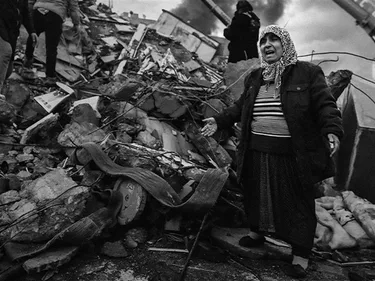 Huilende vrouw op de resten van een verwoest gebouw