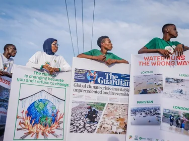 Jongeren houden borden vast met nieuwsartikelen over het klimaat tijdens een demonstratie in Lagos, Nigeria.