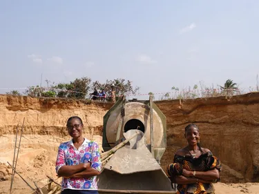 Virginia en een andere vrouw staan bij een brug in aanbouw in Nigeria.