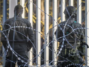 Gemaskerde soldaten achter een muur van prikkeldraad.