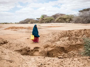 Halima loopt met een jerrycan over een droge vlakte.
