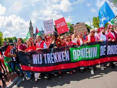 Demonstranten in het rood met spandoek 'Wij trekken opnieuw die rode lijn'
