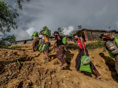Rohingya vluchtelingen dragen hulpgoederen van Oxfam met zich mee