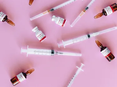 Flesjes met vaccins en injectienaalden liggen door elkaar.