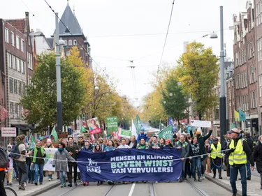 Mensen lopen over straat met borden en spandoeken