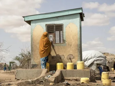Een vrouw haalt water uit een automaat