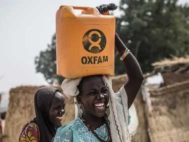 Een man draagt een jerrycan op zijn hoofd met het Oxfam logo.