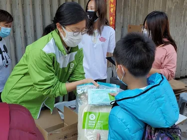 Een vrouw deelt rijst uit aan een jongetje.