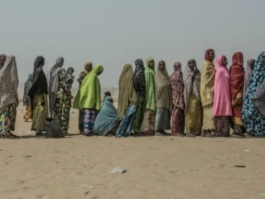 Foto van vluchtelingen in een rij in de woestijn van Niger.