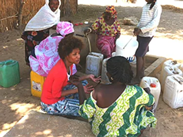 Foto van Sylvana Simons in Senegal zittend op de grond, pratend met de lokale bevolking.