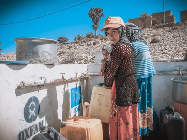Jonge mensen staan bij een waterpunt van Oxfam met jerrycans.