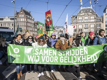 Demonstranten met een spandoek met de tekst: Samen strijden wij voor gelijkheid