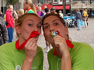 Twee vrouwen kussen hun marathon medaille.