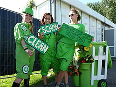 Straatwervers in groene overall met borden waarop het woord 'schoon' staat in meerdere talen.