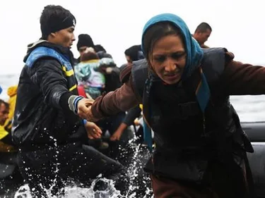 Vluchtelingen stappen uit een rubberboot en komen aan op Lesbos.