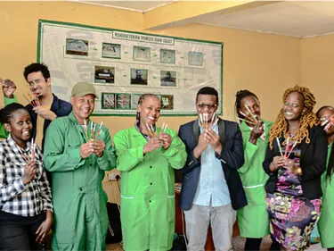 Lachende medewerkers van Recycle Pens & Pencils houden pennen en potloden vast. Recycle Pens & Pencils is een SME-bedrijf uit Kenia.