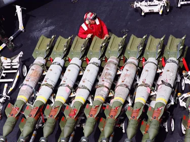 Een militair staat bij een rij vliegtuigbommen.
