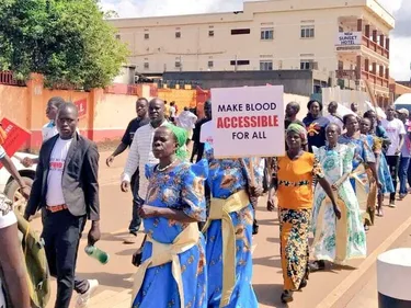 Demonstranten op staat in Uganda. Op een protestbord staat: Make blood accessible for all.