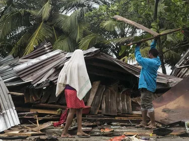 Ingestorte huizen in de Dominicaanse Republiek na orkaan Irma. Twee mensen lopen erbij.