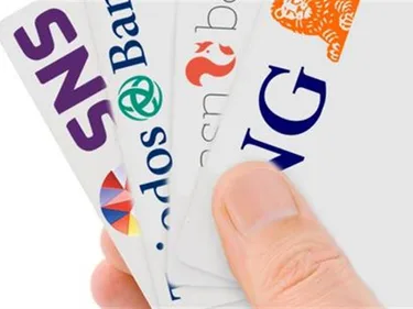 Foto van een hand met daarin bankpasjes van verschillende banken.