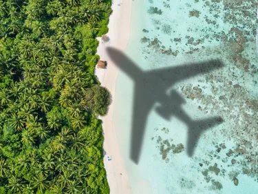 Een vliegtuig vliegt over een tropisch strand