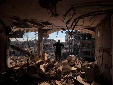 Man staat in zijn verwoeste appartement in Gaza