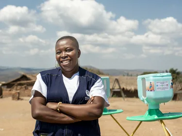 Pascaline Namegabe, medewerker volksgezondheid van Oxfam, demonstreert de nieuwe handwasstand aan de gemeenschap in het vluchtelingenkamp Mwaka