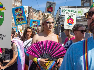 Een drag queen tussen mensen met protestborden tijdens Pride demonstratie