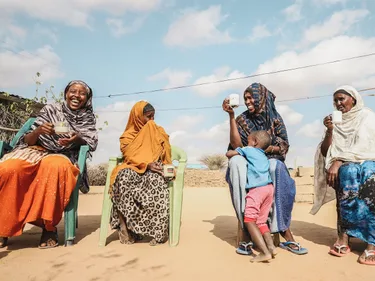 Vier Keniaanse vrouwen zitten naast elkaar iets te drinken.