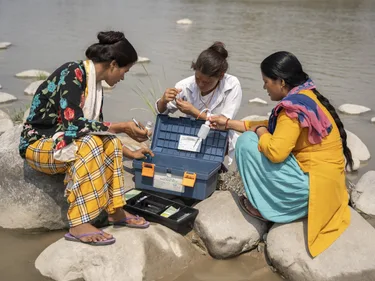 Anjala Devi Bohra en twee vrouwen testen het rivierwater.
